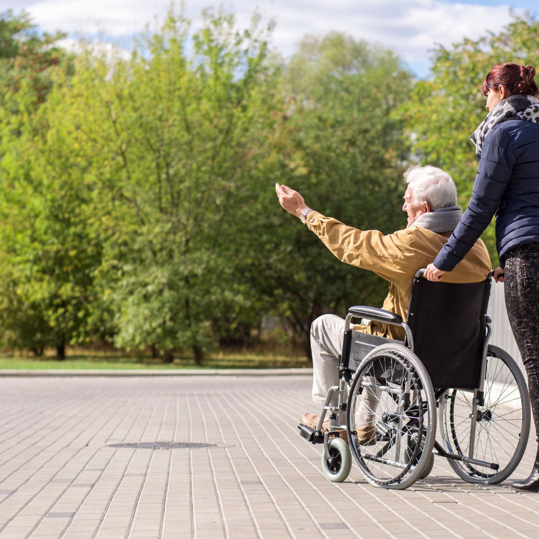 Woman walking an elderly man in a wheelchair